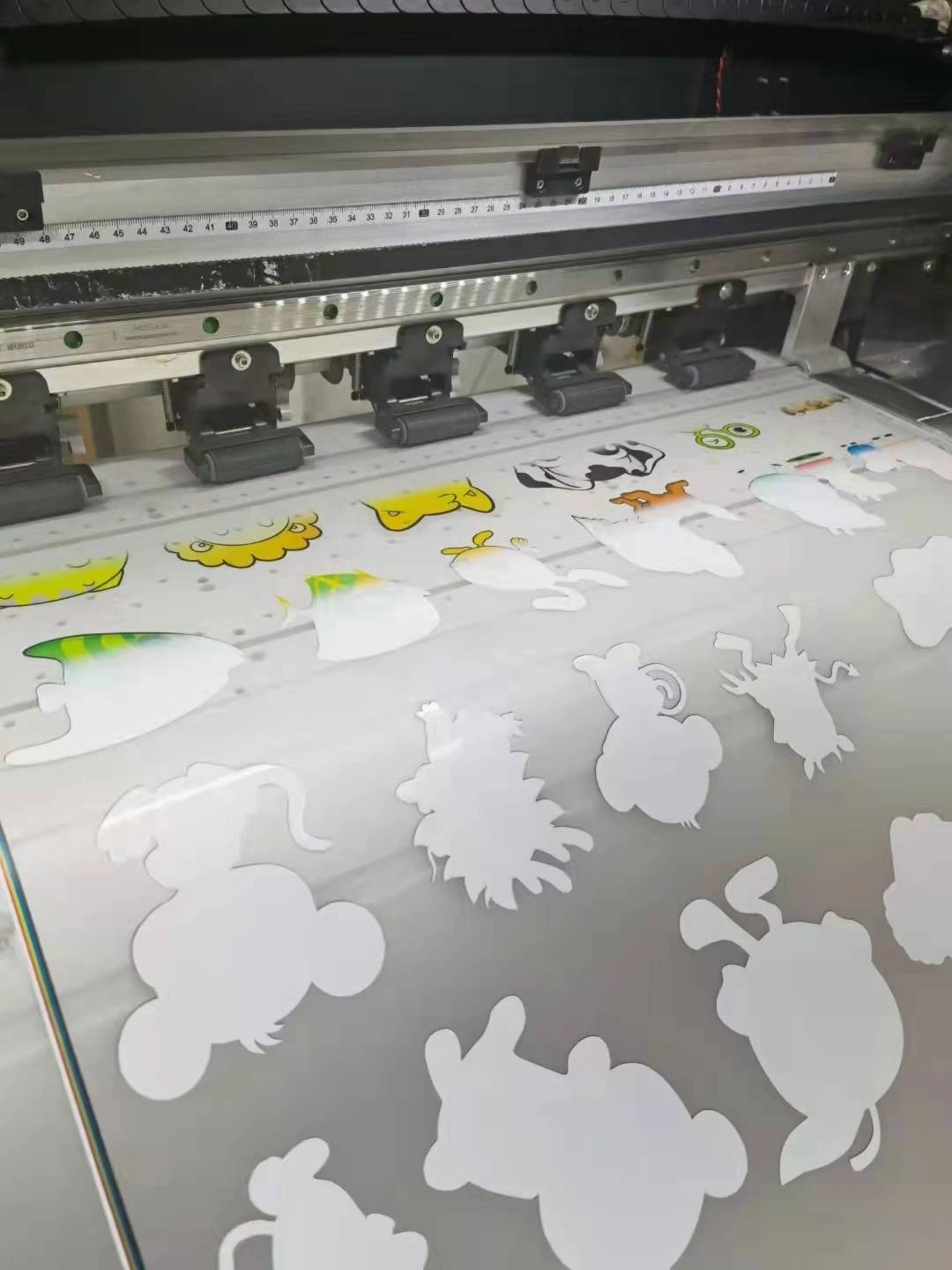 DTF printer showing white ink cartoon outlines bleeding on coated PET film during production.